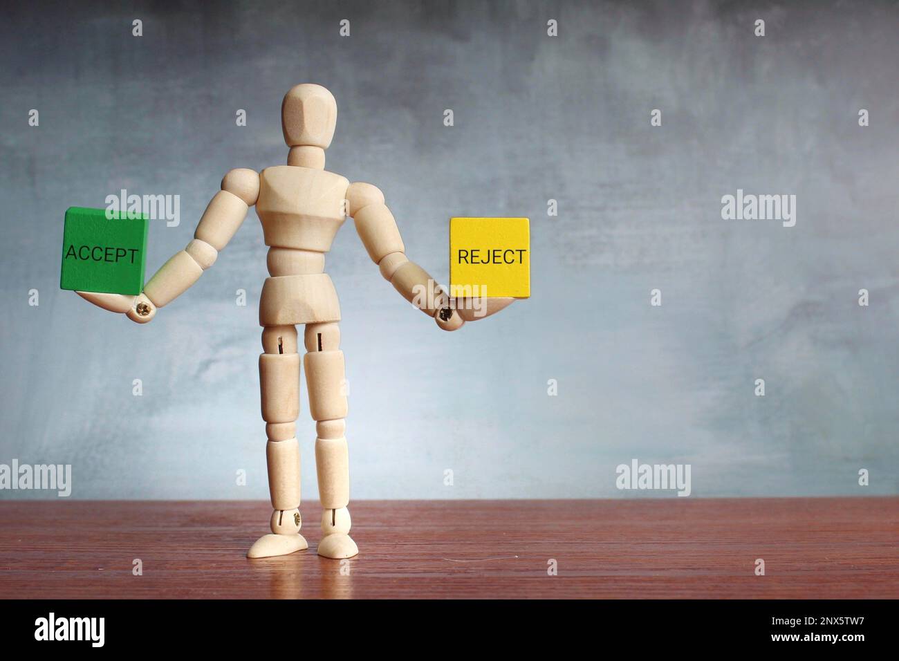 Wooden human figure balancing wooden cubes with text ACCEPT and REJECT. Choice, option, survey concept. Stock Photo