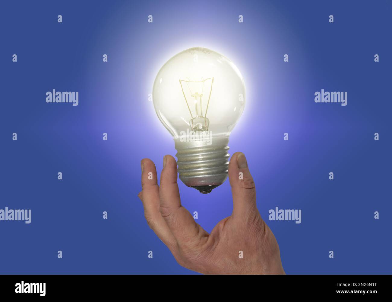 The hand holds a glowing electric light bulb. Stock Photo