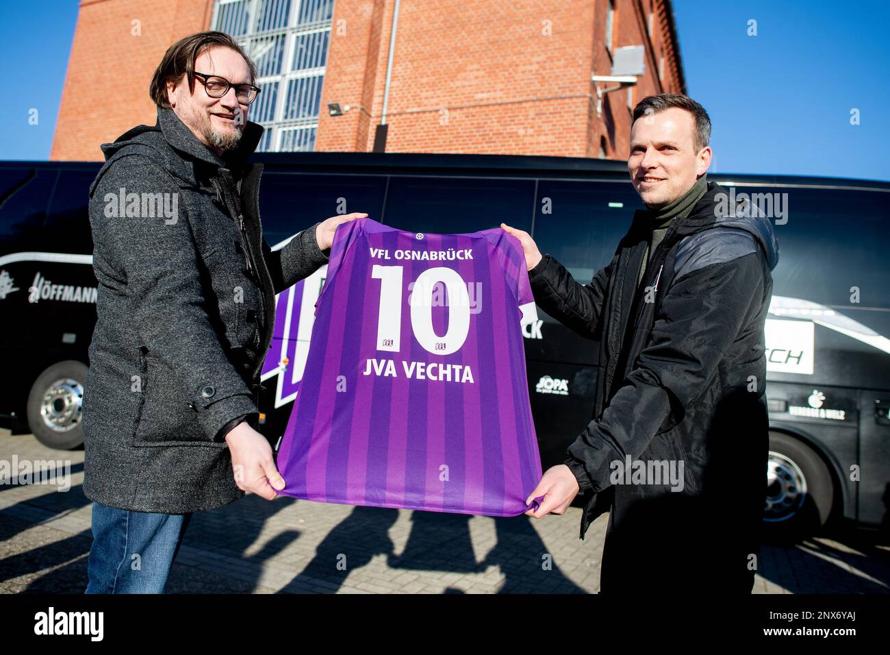 Vechta, Germany. 28th Feb, 2023. Michael Welling (l), managing director of VfL Osnabrück, and Sebastian Rüther, press officer of VfL Osnabrück, stand in the courtyard of the correctional facility for young offenders with a jersey of the club. The Vechta correctional facility and VfL Osnabrück have presented their cooperation in the initiative 'Anstoß für ein neues Leben' (impetus for a new life). The project of the Sepp Herberger Foundation of the German Football Association (DFB) is about the resocialization of young prisoners. Credit: Hauke-Christian Dittrich/dpa/Alamy Live News Stock Photo