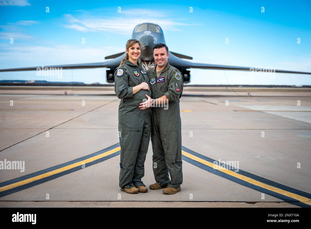 U.S. Air Force Maj. Lauren Olme, 77th Weapons Squadron assistant director of operations, and her husband, Maj. Mark Olme, 7th Operations Support Squadron bomb wing weapons officer, pose for a photo next to a B-1B Lancer at Dyess Air Force Base, Texas, Feb. 20, 2023. Lauren, who is currently pregnant, can continue flying after recently getting approved under the Air Force’s new guidance which allows female aircrew members to voluntarily request to fly during pregnancy. No waiver is required to fly in the second trimester with an uncomplicated pregnancy in a non-ejection seat aircraft if all fli Stock Photo