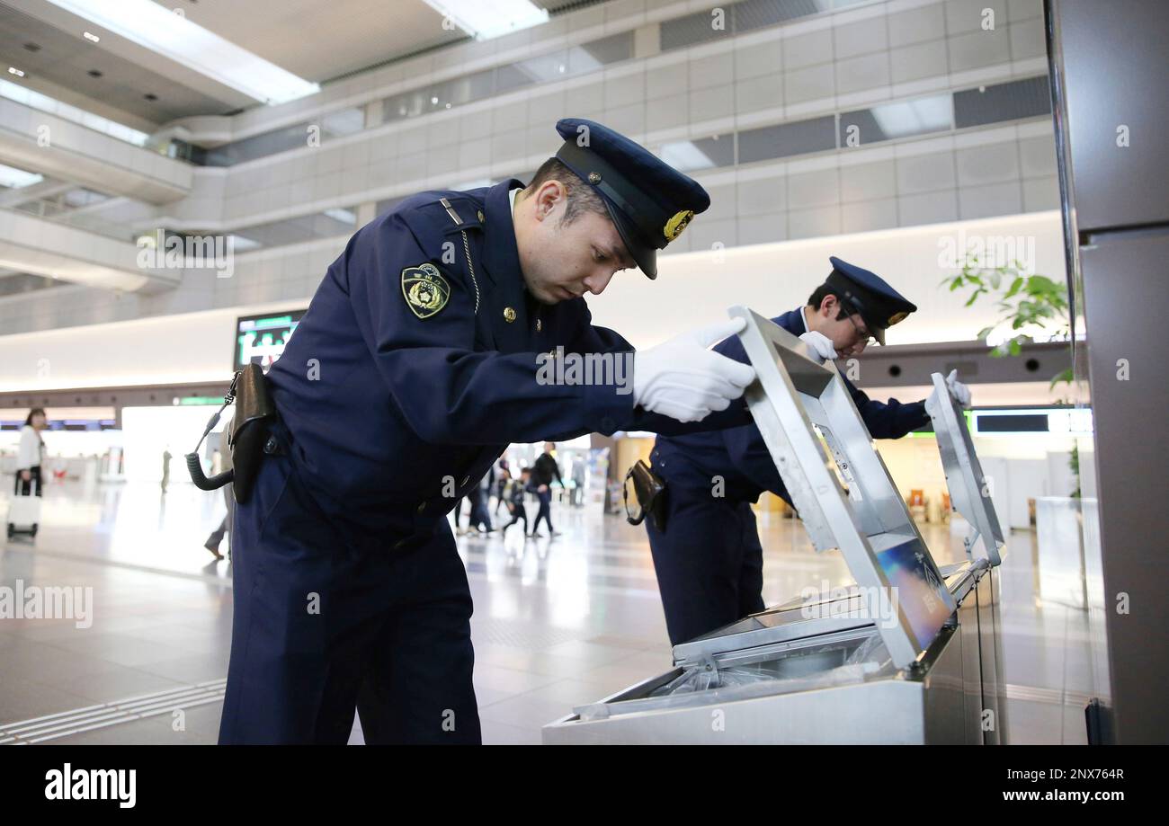Riot police officers investigate trash boxes at Haneda International