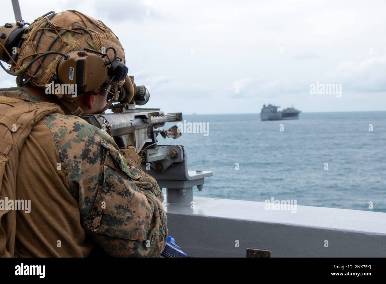 NATUNA SEA (Jan. 7, 2023) – A Marine assigned to a Surveillance and Target Acquisition (STA) platoon embarked aboard amphibious transport dock USS Anchorage (LPD 23) watches over Marines engaged in a Visit, Board, Search, and Seizure (VBSS) training exercise aboard Lewis B. Puller-class expeditionary mobile base USS Miguel Keith (ESB 5), Jan. 7. Synchronizing the complementary capabilities of the 13th Marine Expeditionary Unit (MEU) and USS Anchorage multiplies the traditional influence of sea power to produce a more competitive and lethal force. The Makin Island Amphibious Ready Group, compri Stock Photo