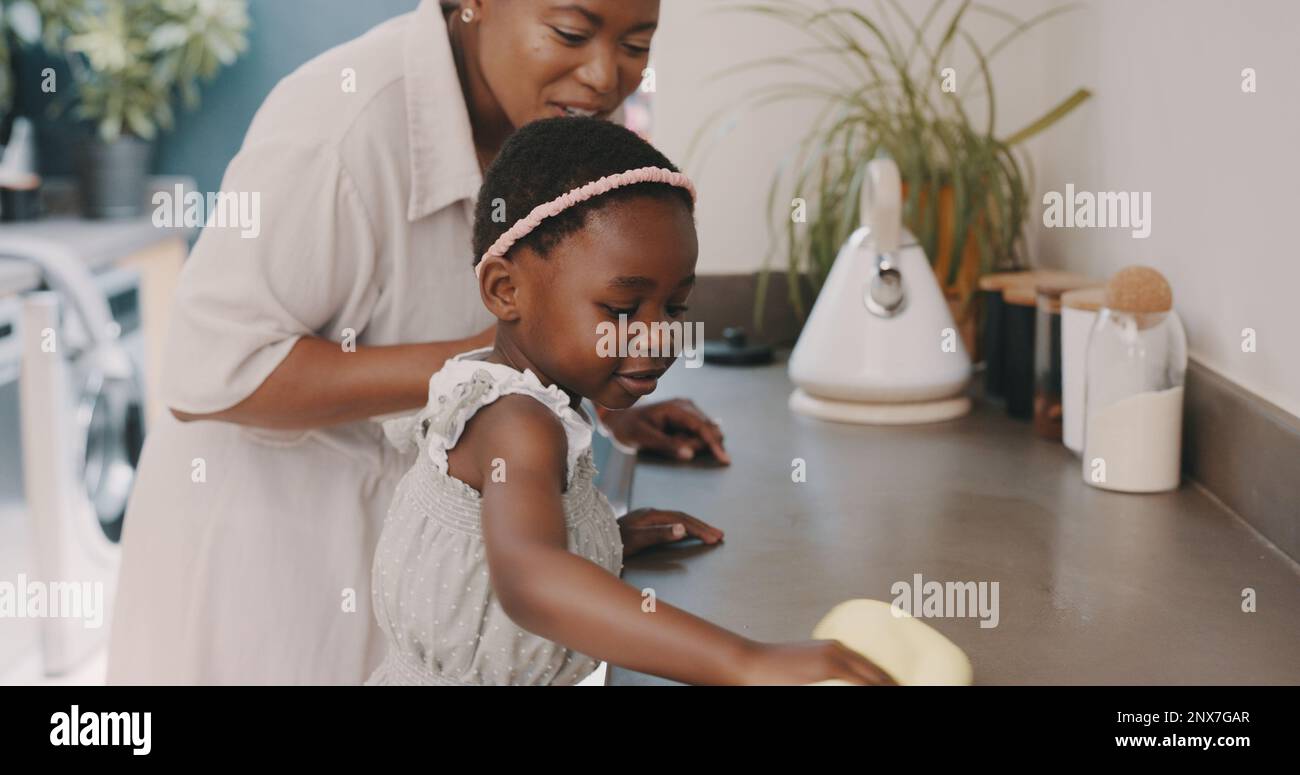 Little girl helping her mother with household chores at home. Happy mom ...