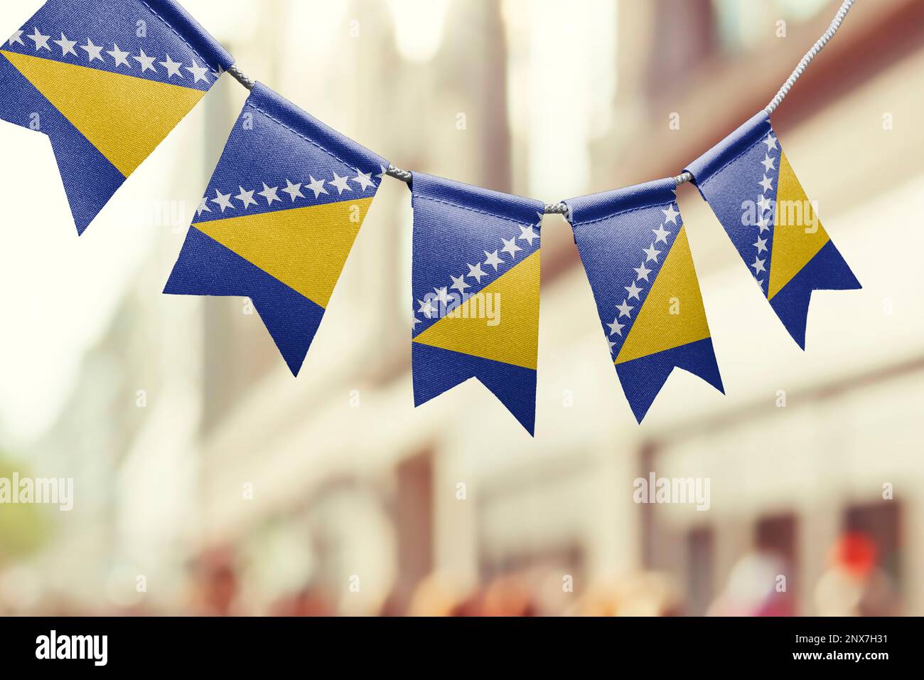 A garland of Bosnia and Herzegovina national flags on an abstract ...