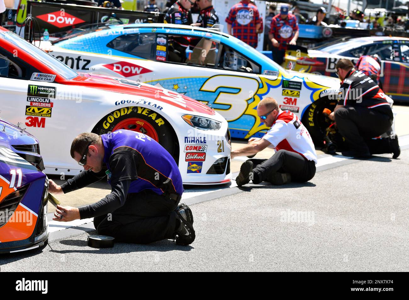 Crews tape up the front of cars during qualifying for the NASCAR