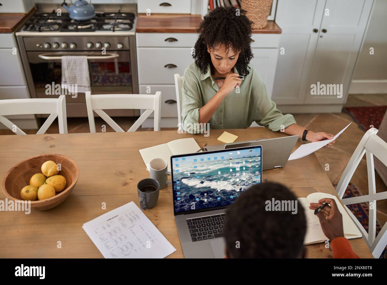 Multiracial couple working remotely from home at a kitchen table Stock Photo