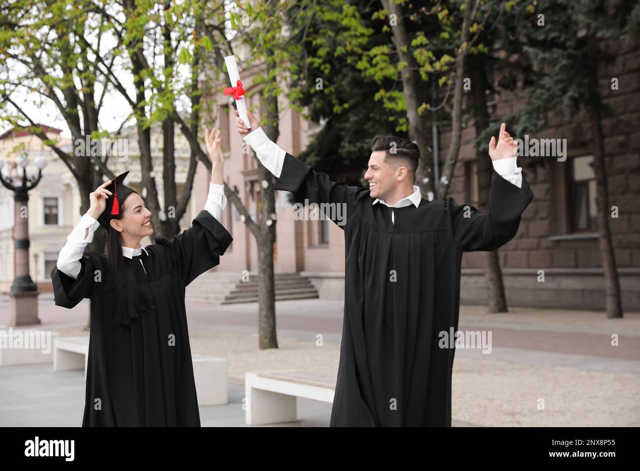 Happy students with diplomas after graduation ceremony outdoors Stock Photo
