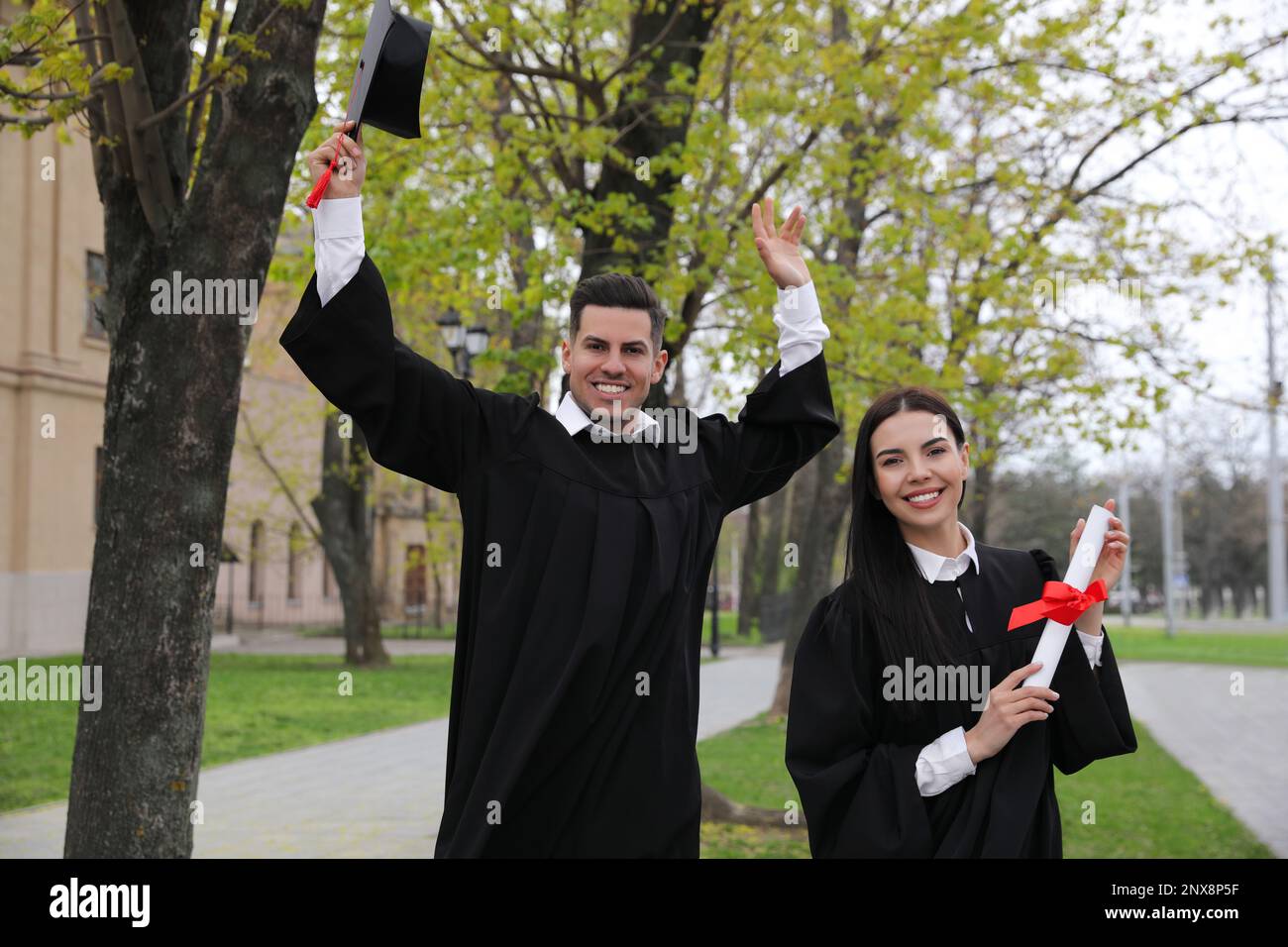 Happy students with diplomas after graduation ceremony outdoors Stock Photo