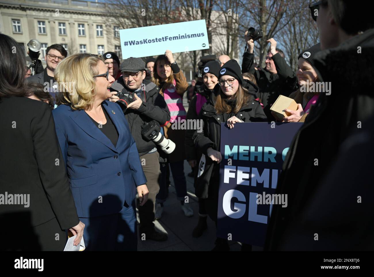 Berlin, Germany. 01st Mar, 2023. Svenja Schulze (SPD, l), Federal Minister for Economic Cooperation and Development, stands on the sidelines of her presentation of the Guidelines on Feminist Foreign Policy with Foreign Minister Baerbock (hidden) in front of people protesting with a sign reading '#Was kostet Feminismus' in front of the Federal Chancellery. Credit: Britta Pedersen/dpa/Alamy Live News Stock Photo