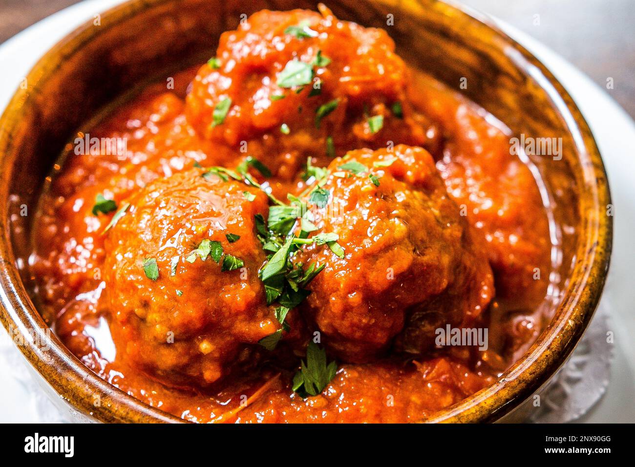 https://c8.alamy.com/comp/2NX90GG/spanish-cuisine-traditional-homemade-meatballs-in-rich-tomato-sauce-served-with-fresh-basil-tapas-in-a-rustic-terracotta-dish-2NX90GG.jpg
