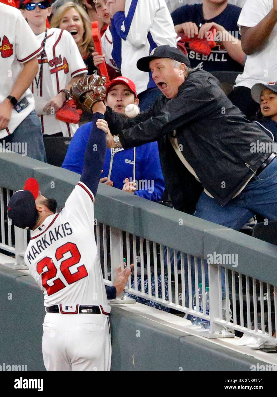 A fan interferes with Atlanta Braves right fielder Nick Markakis (22) who  tries to catch a foul ball by New York Mets' Asdrubal Cabrera in the sixth  inning of a baseball game