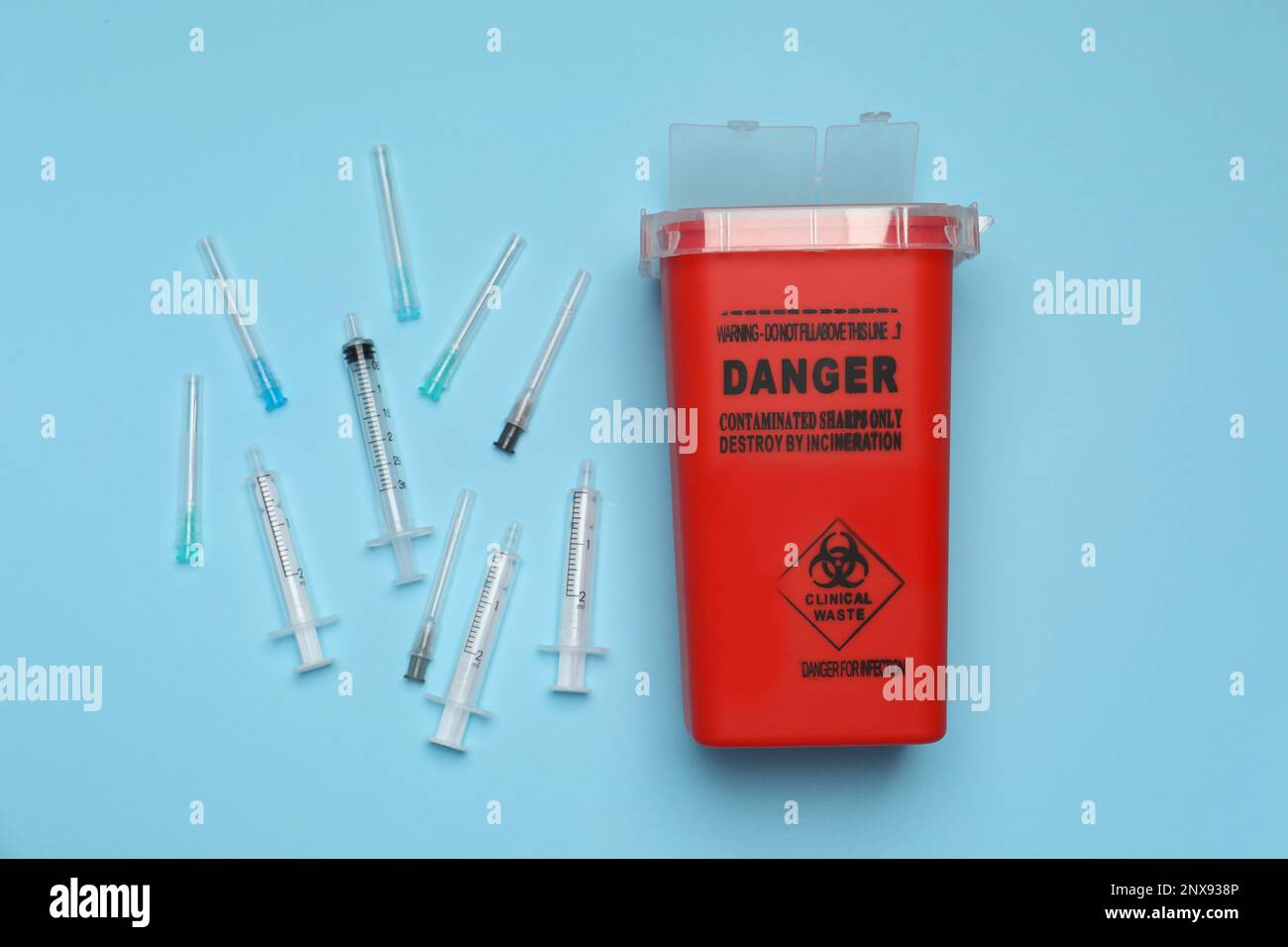 Disposable syringes, needles and sharps container on light blue