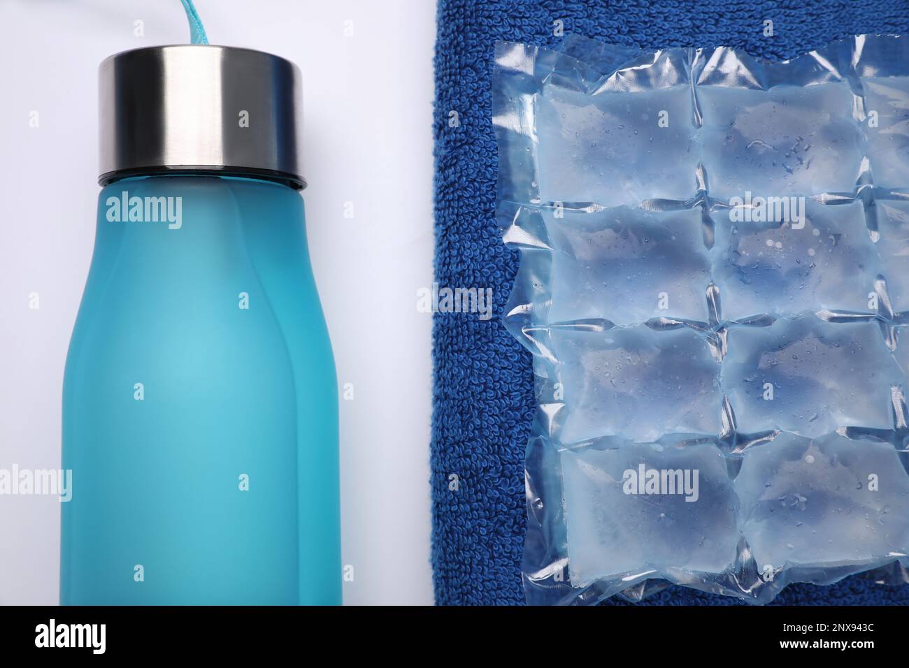 Bottle of water, ice pack and towel on white background, flat lay. Heat
