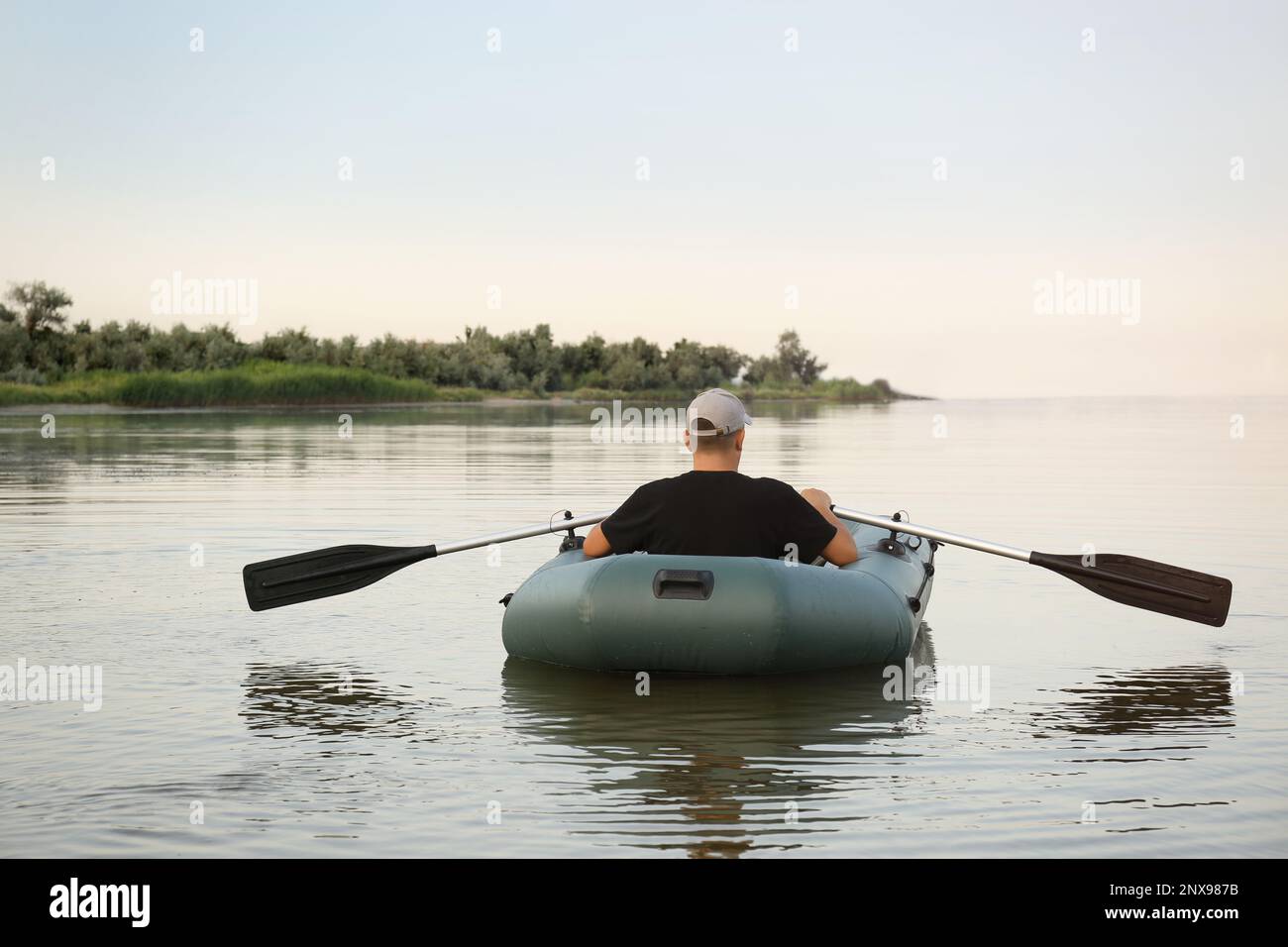 Man rowing inflatable rubber fishing boat on river, back view Stock