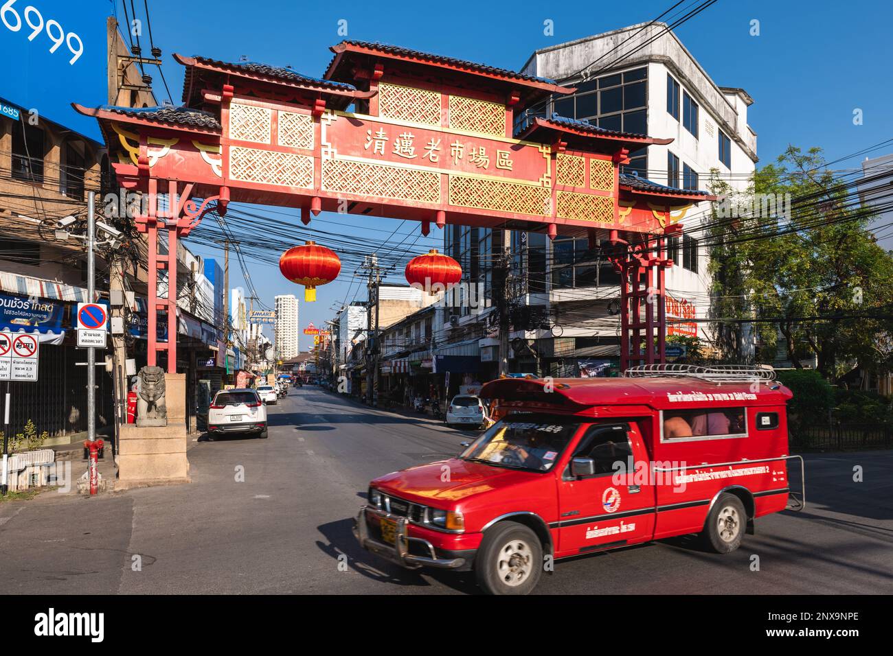 February 12, 2023: A red truck pass by the Chinese welcome gate of Chinatown, the oldest trading quarter of Chiang Mai in Thailand, features several m Stock Photo