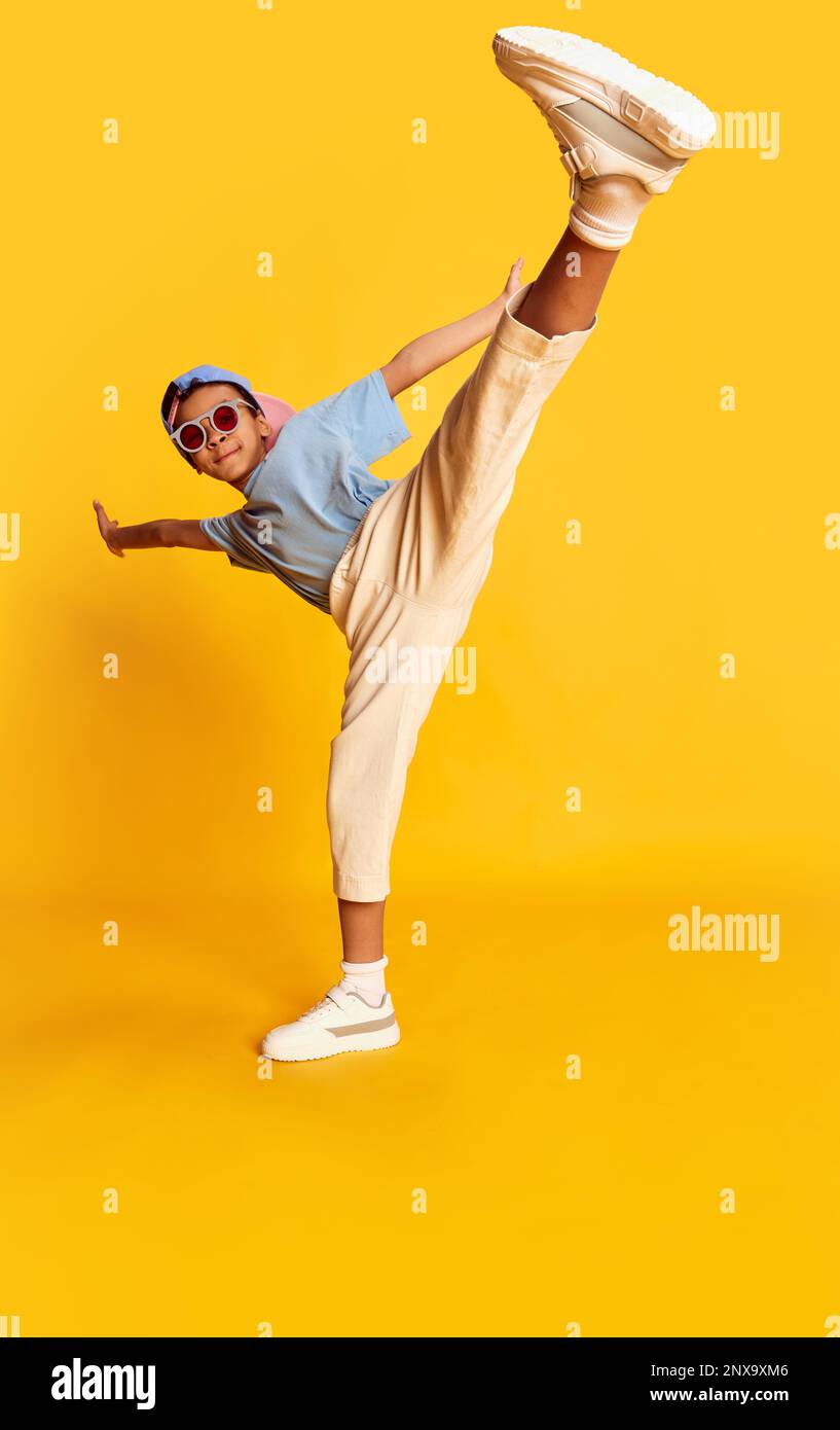 Dynamic portrait of little african boy, hiphop dancer in stylish street style clothes dancing