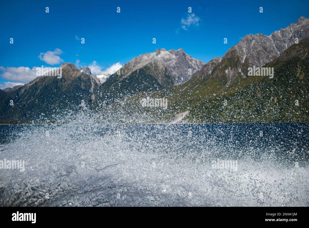 Spray from a sppedboat as it travels down the Fiord parallel to the Holyford Track, Fiordland, South Island, New Zealand. Stock Photo