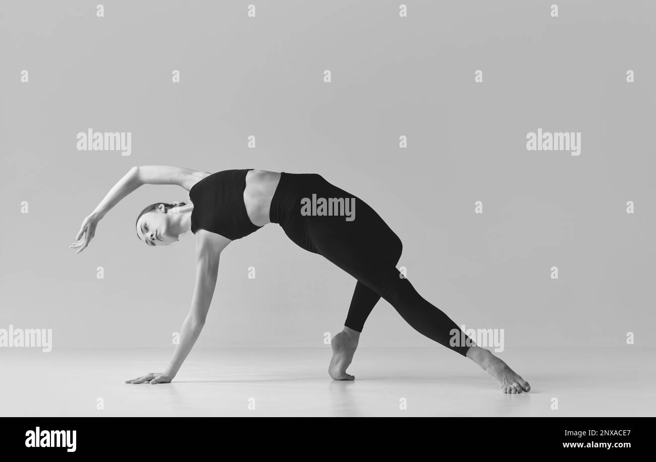 Flexibility. Black and white photography. Young slim, fit girl training