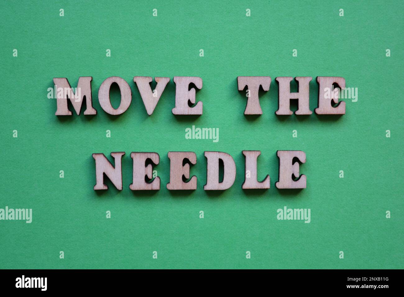 Move The Needle, phrase in wooden alphabet letters isolated on green background Stock Photo