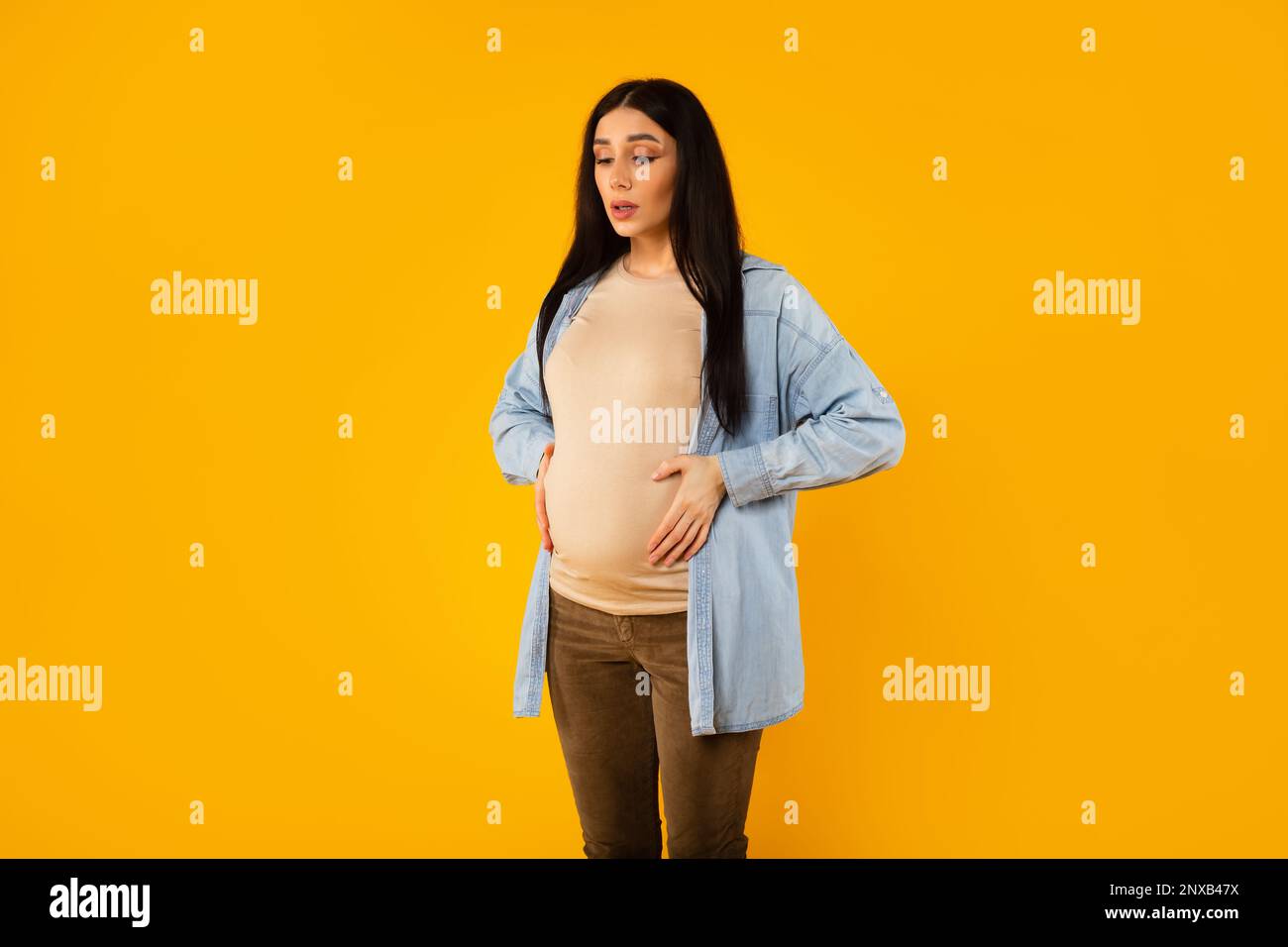 Pregnant lady having painful spasm and touching belly, doing breathing