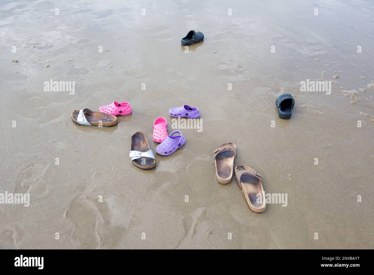 Overhead view of five pairs of sandals on a beach in summer Stock Photo