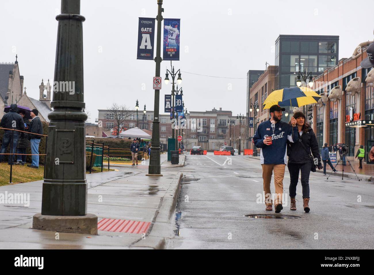 Waleed Faraj, of Dearborn Heights, Mich., carries an umbrella for himself  and Jessica Lopez, of Canton, outside of Comerica Park after it was  announced that the Detroit Tigers' opening day baseball game