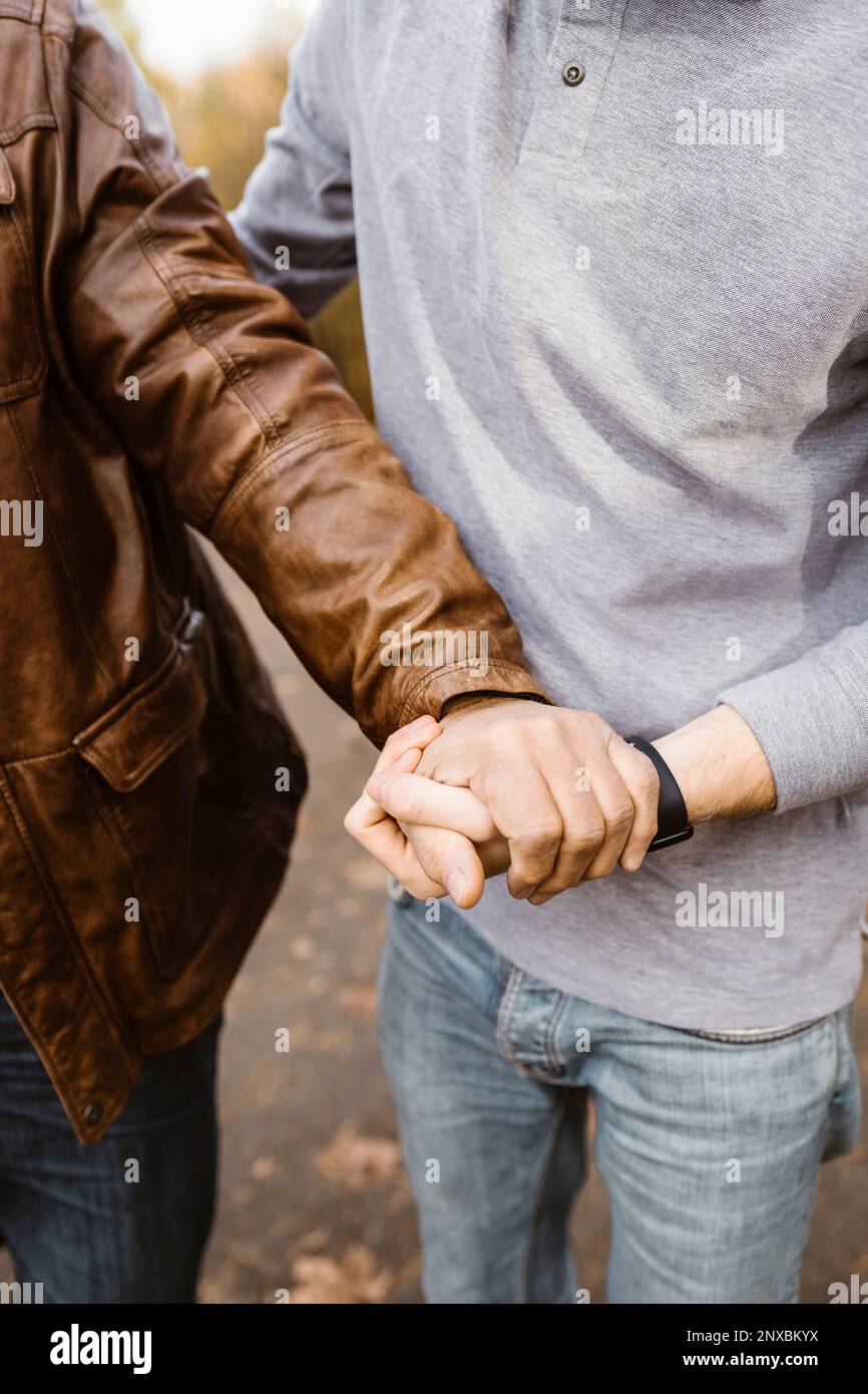 Midsection of young man holding hand of retired senior father Stock Photo