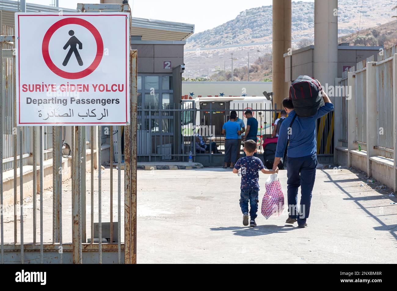 Man and child refugee returning to the secured area in his country. Syrian refugees cross into Syria through the Cilvegözü border gate in Turkey. Stock Photo