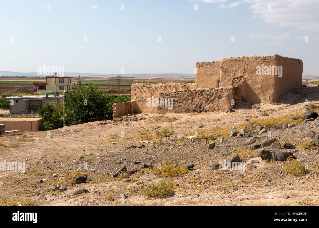 Old adobe house and modern buildings nearby. A house made of adobe, which was used frequently in Anatolia in the recent past. Kilis, Turkey. Stock Photo