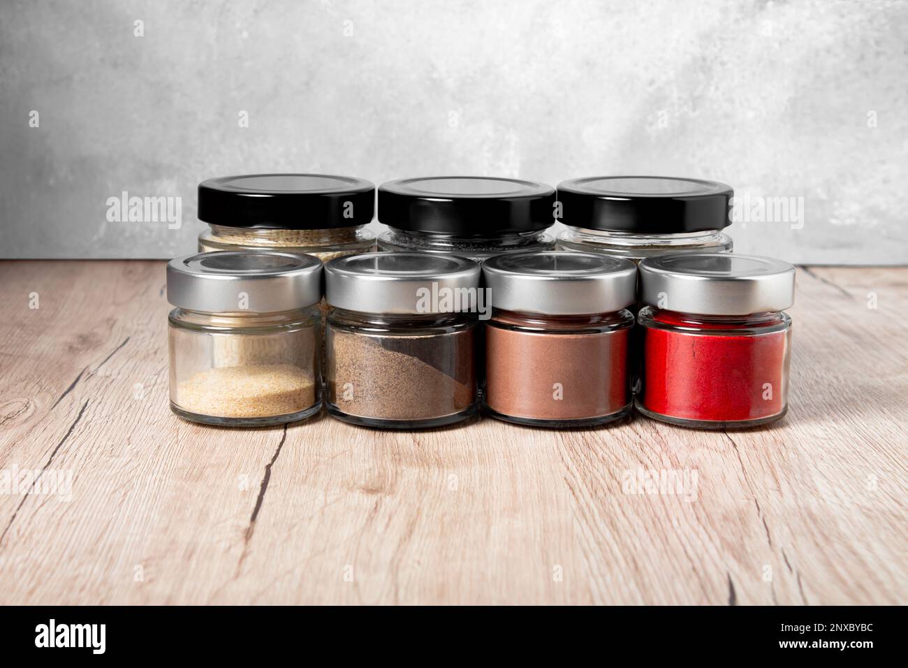 Bright fragrant spices in glass jars of different sizes on a wooden
