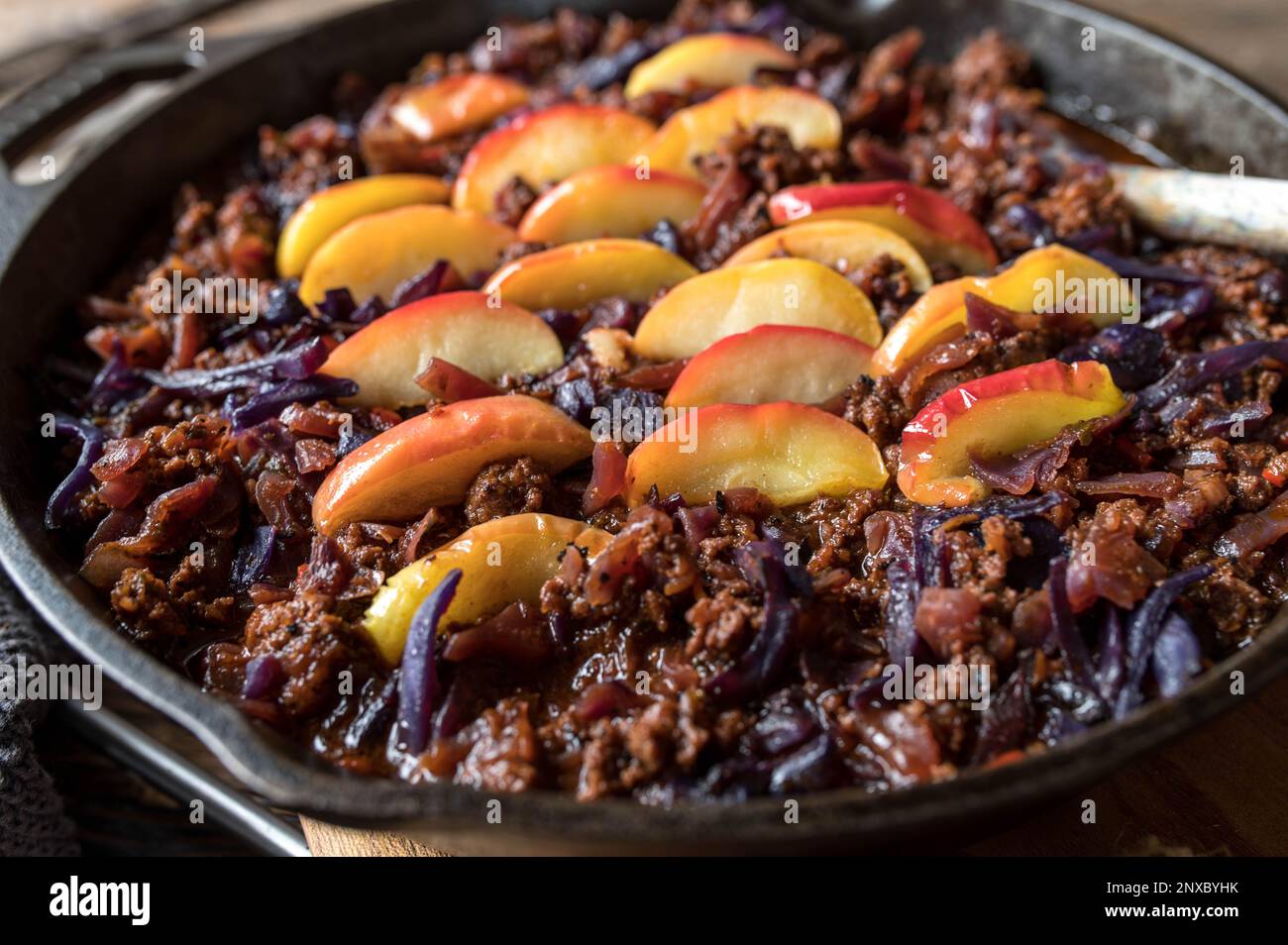 Ground beef cabbage stew with butter fried apple topping in a cast iron