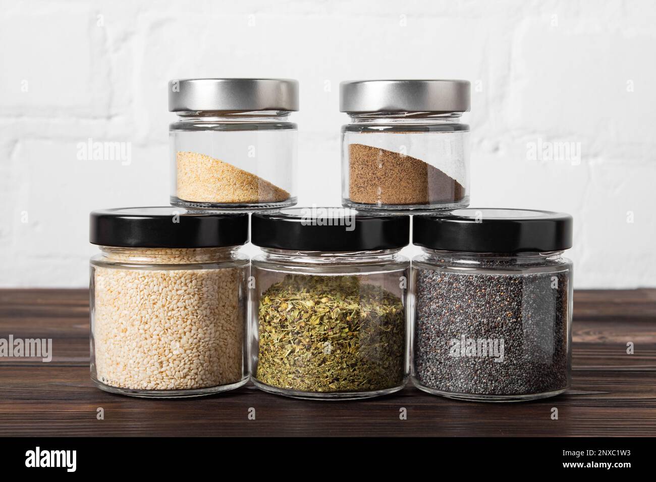 Bright fragrant spices in glass jars of different sizes on a wooden