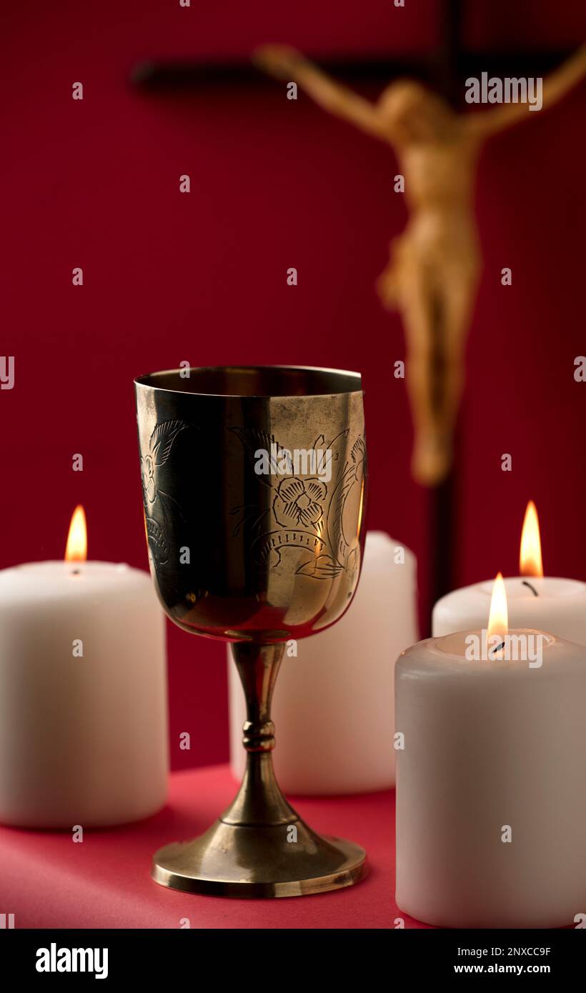 golden chalice with crucifix and burning candles red background Stock