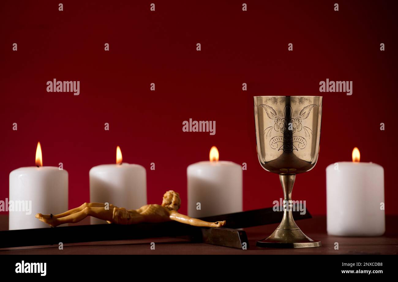 golden chalice with crucifix and burning candles red background Stock