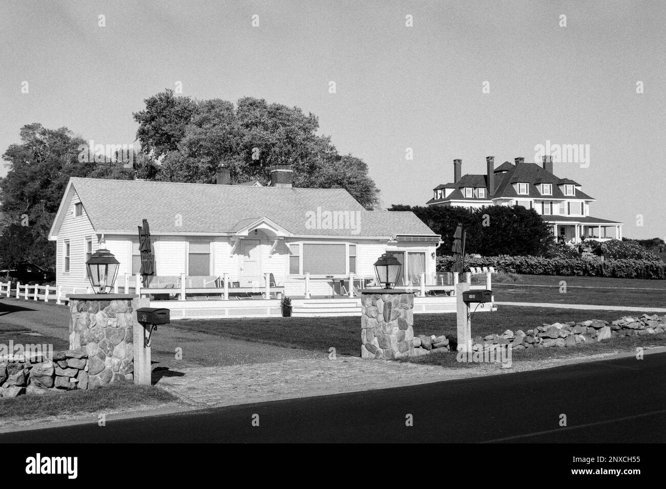 A bright beach home with stone pillars marking the driveway with a