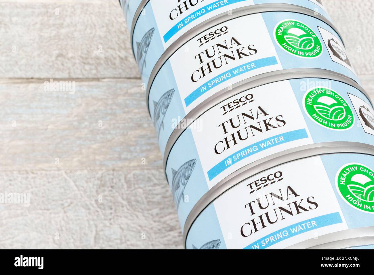 Stacked cans of tinned Tesco Tuna chunks on a kitchen table. For UK