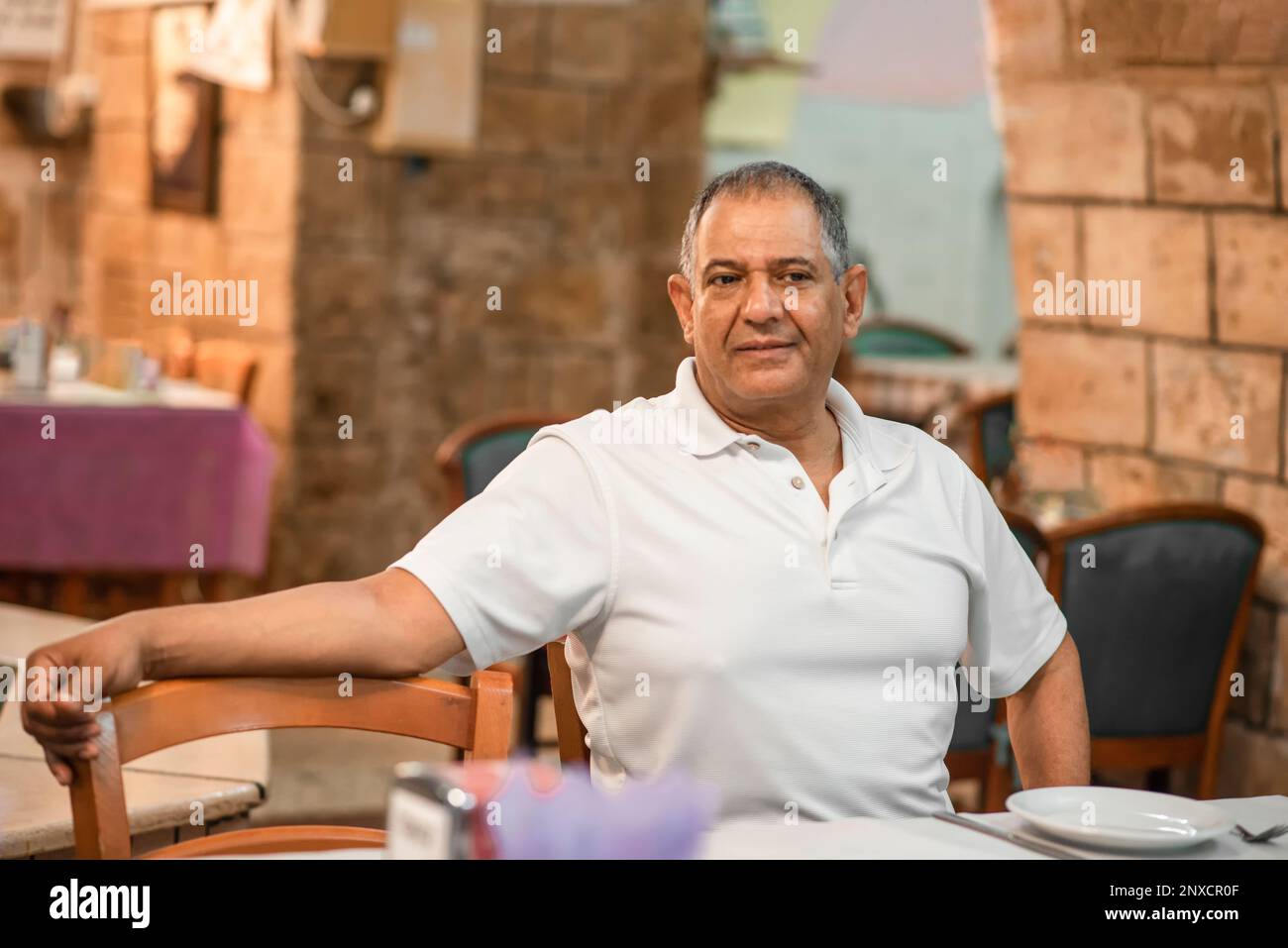 Portrait middle eastern senior man sitting in a restarant and looking in camera. Stock Photo
