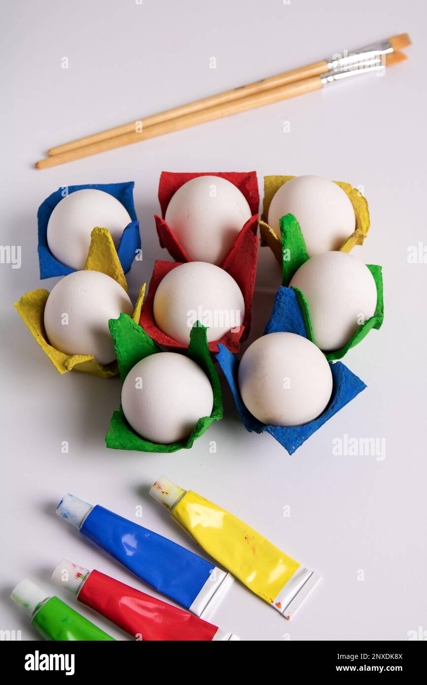 photo paint tube , brushes and eggs in colored packages on white package Stock Photo