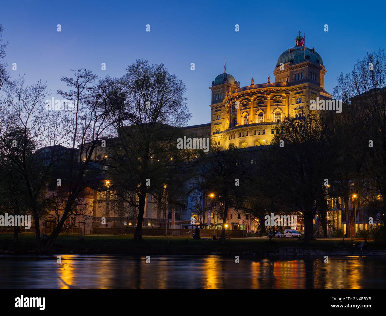 Berne, Switzerland - April 15th 2023: Evening view over the Aare river towards Bundeshaus, lighted during blue hour Stock Photo