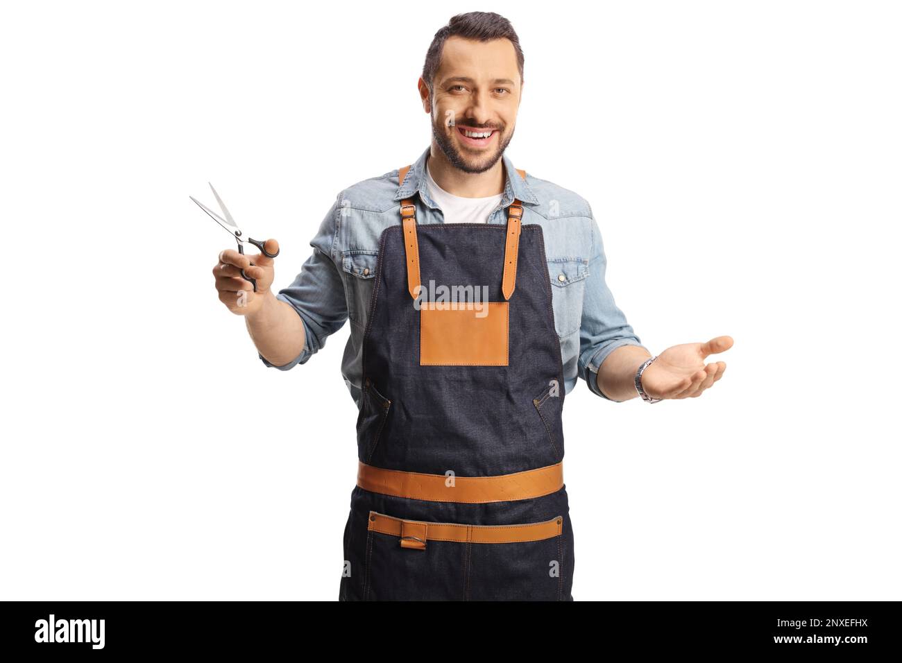Male hair stylist wearing an apron and holding a pair of scissors isolated on white background Stock Photo