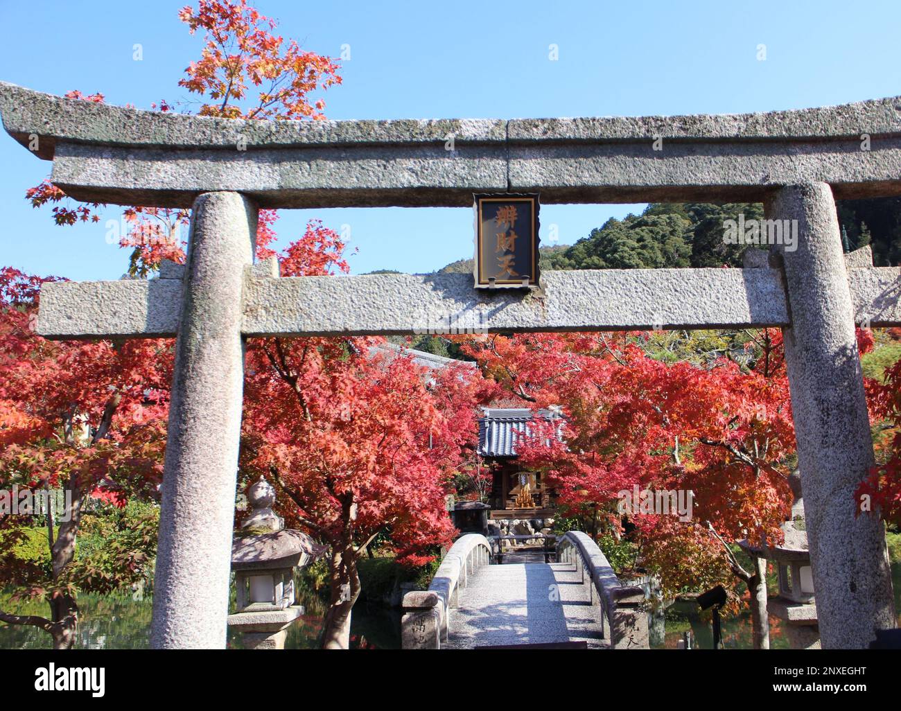 Autumn leaves, a bridge and stone Torii (with the name of god) in the garden of Eikando temple, Kyoto, Japan Stock Photo