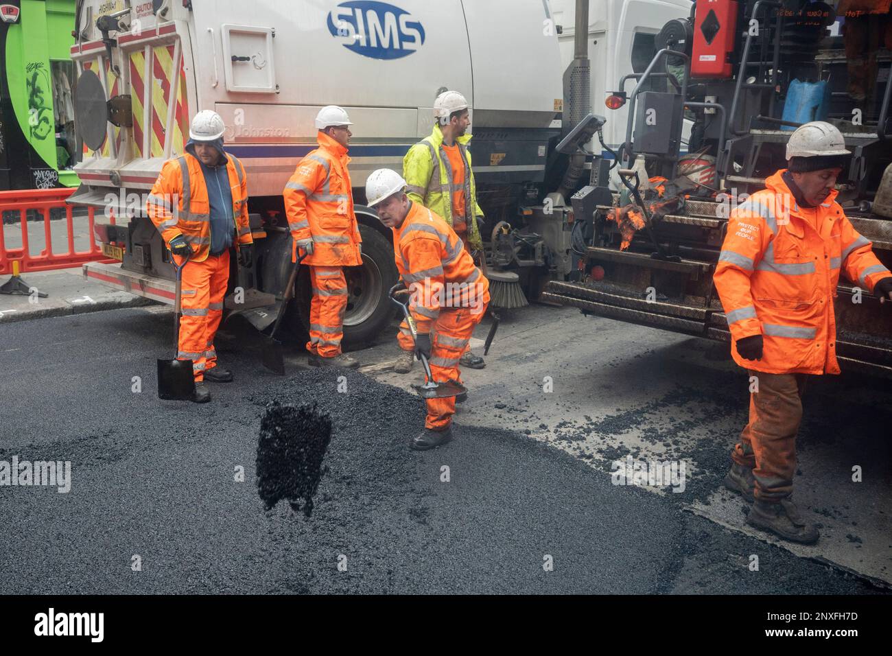 Workmen with the contractor, VolkerHighways resurface a stretch of the closed Charing Cross Road near the junction of Tottenham Court Road, on 1st March 2023, in London, England. Stock Photo