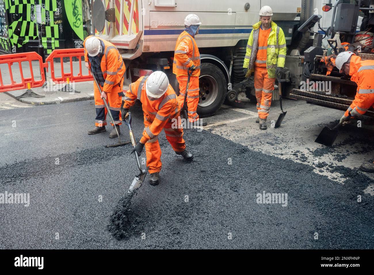 Workmen with the contractor, VolkerHighways resurface a stretch of the closed Charing Cross Road near the junction of Tottenham Court Road, on 1st March 2023, in London, England. Stock Photo