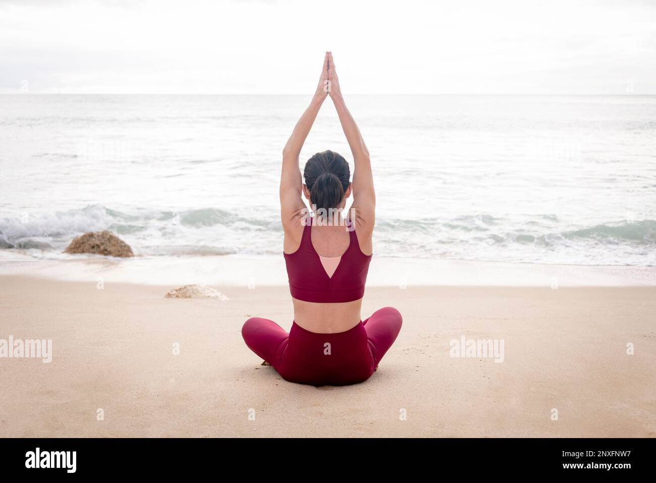 woman sitting on the beach and meditating, rear view. Stock Photo