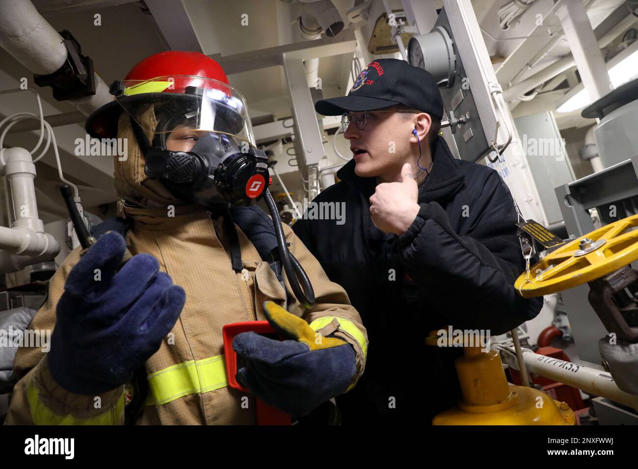 PACIFIC OCEAN (Jan. 28, 2023) – Machinery Repairman 1st Class Gage Jones (right), from Boise, Idaho, gives feedback to Operations Specialist 3rd Class Lanette Barnes, from Chesapeake, Virginia, during a general quarters drill in a main engine room aboard the Arleigh Burke-class guided-missile destroyer USS Rafael Peralta (DDG 115) while operating in the Pacific Ocean, Jan. 28. Rafael Peralta is assigned to Commander, Task Force 71/Destroyer Squadron (DESRON) 15, the Navy’s largest forward-deployed DESRON and the U.S. 7th Fleet’s principal surface force. Stock Photo