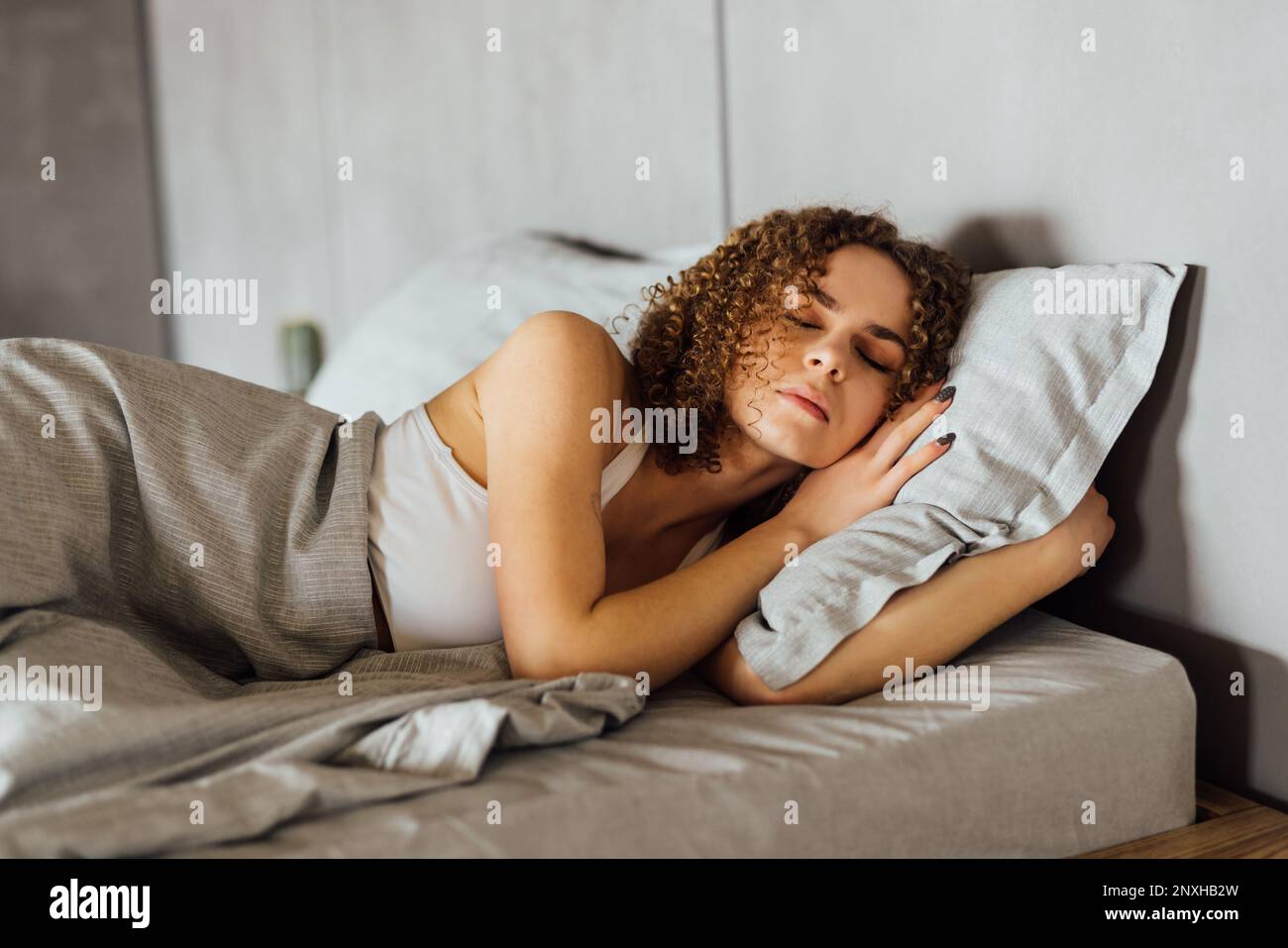 Feeling calmness. Sleepy female keeping eyes closed while dreaming about future vacation or sleeping at the bedroom. Stock Photo