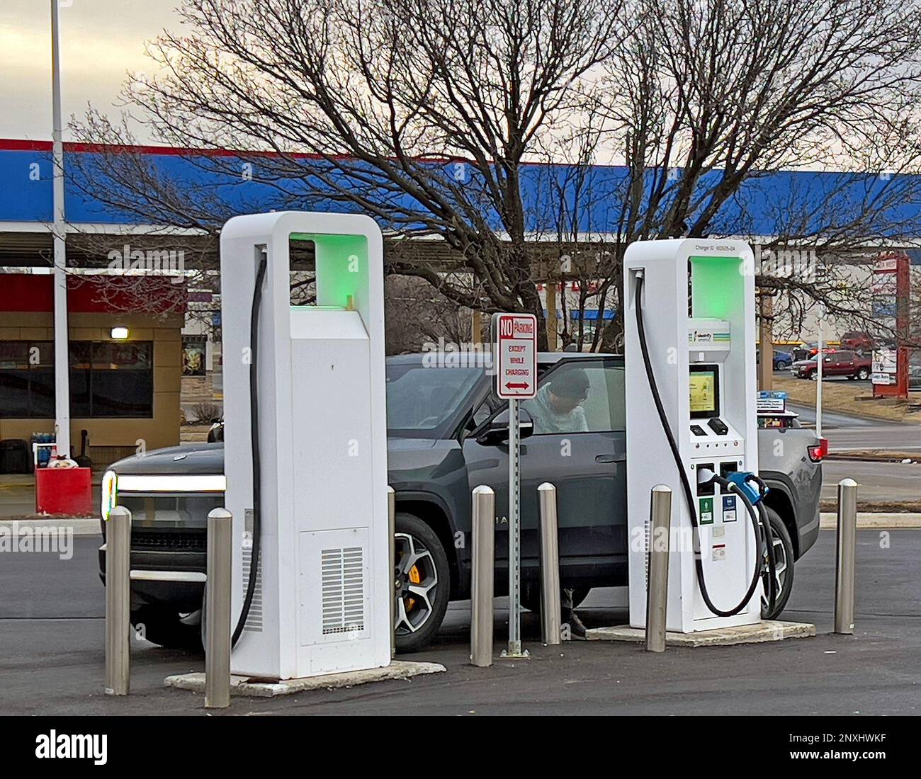 TOPEKA, KANSAS - FEBRUARY 24, 2023 The owner of a new Rivian R1T pickup truck gets out of the truck prior to plugging in his new EV type truck to one of the newly installed Evergy 350 KW Superchargers located in the Walmart parking lot just yards away from the Murphy gas station Stock Photo