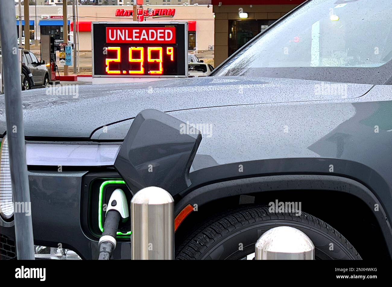 TOPEKA, KANSAS - FEBRUARY 24, 2023 A new Rivian R1T pickup truck is plugged into  one of the newly installed Evergy 350 KW Superchargers located in the Walmart parking lot with the Murphy gas station price sign visible in the background showing the current cost of a gallon of regular unleaded gasoline Stock Photo