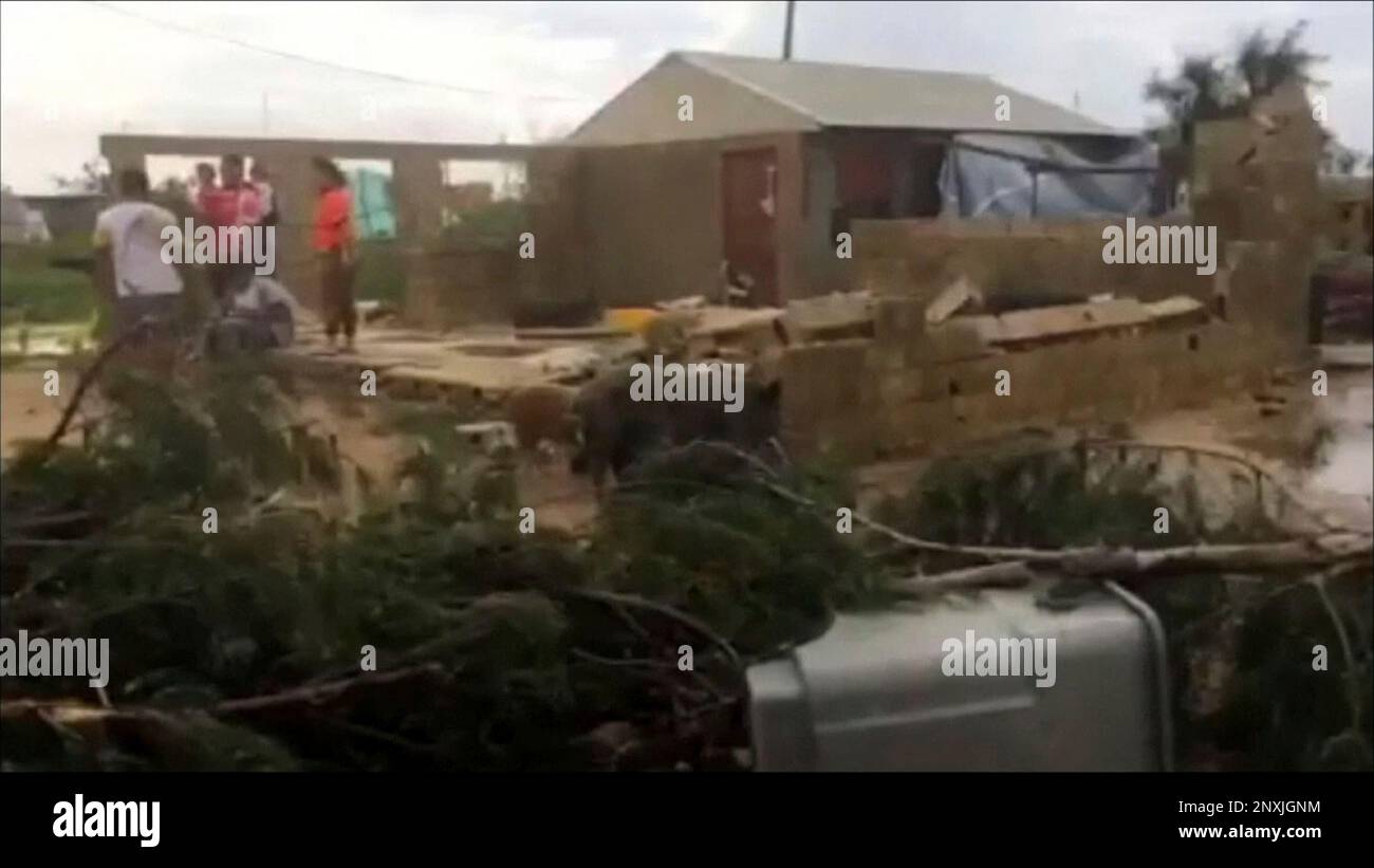 In this image made from a video, people stand near a house damaged by