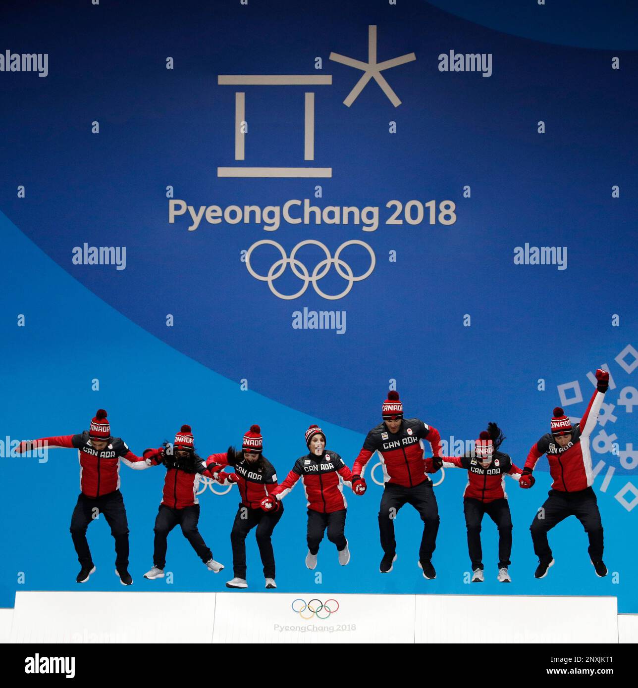 Team figure skating gold medalists from Canada jump in celebration